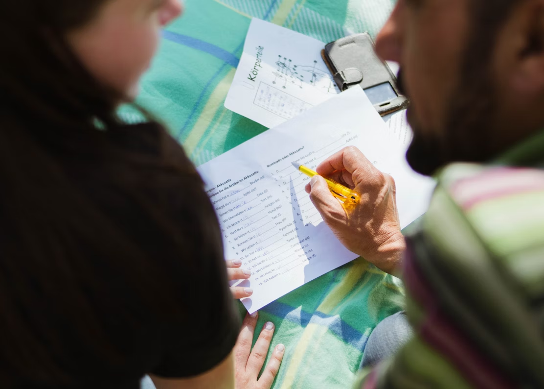 Two people sitting together, reading from a piece of paper with focused attention