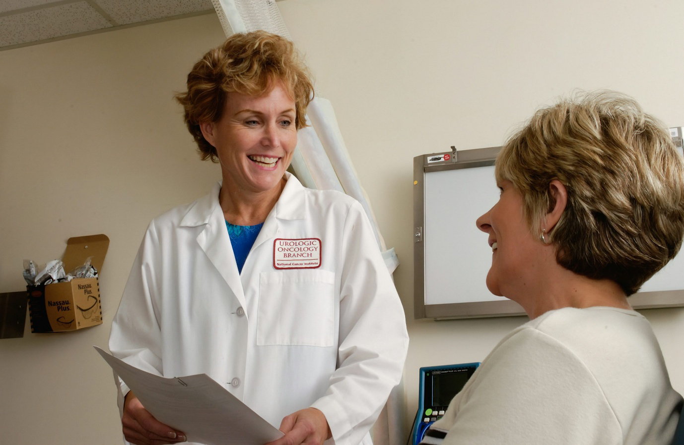 A doctor holding paperwork while talking to a patient